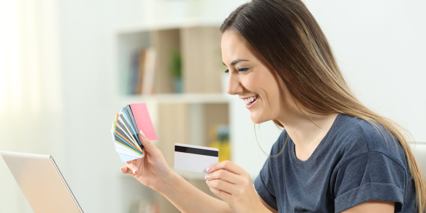 woman holding credit cards looking at laptop