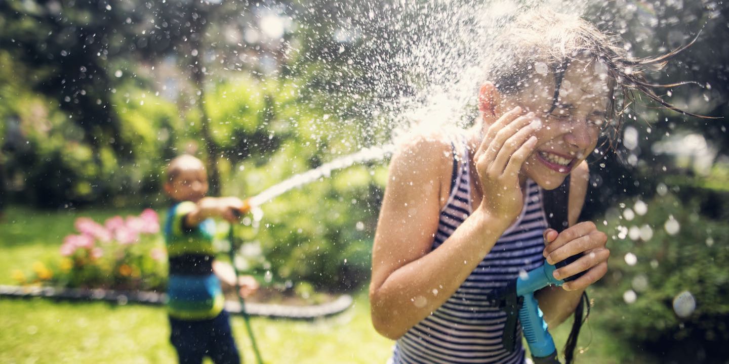 boy spraying girl with water hose