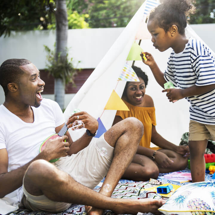 Black family enjoying backyard blowing bubbles